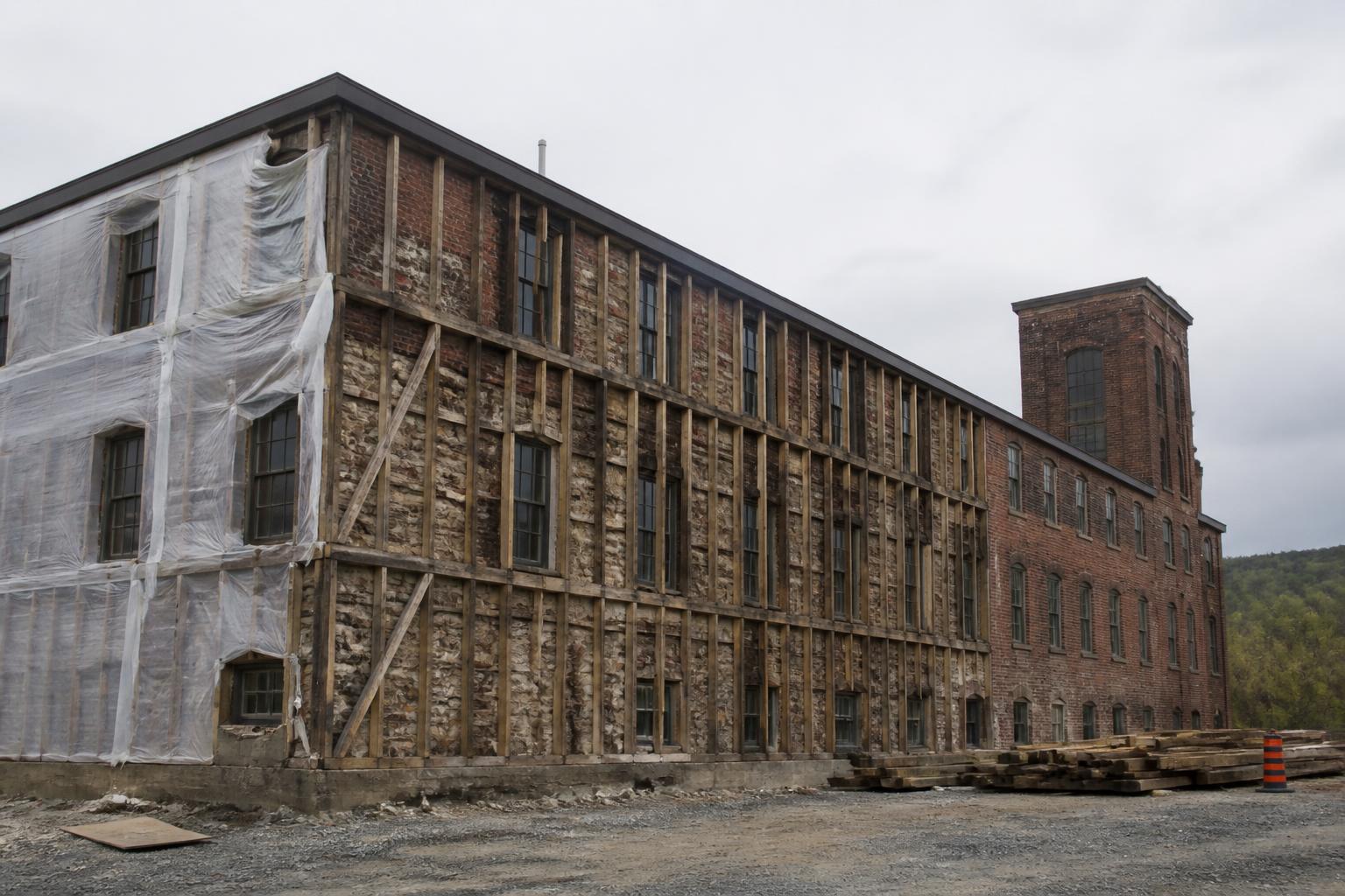A century-old building mid-restoration with siding stripped back